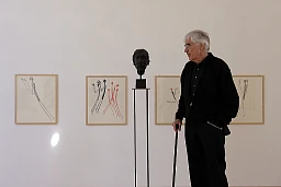 Schang Hutter vor einer Plastik und Bildern seiner Ausstellung