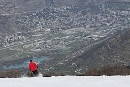 Ein Skifahrer fährt einen Hang in Nendaz hinunter und hat einen Blick aus der Vogelperspektive auf die Stadt Sion