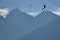 Une personne traverse la ville de Martigny sur une tyrolienne Une personne traverse la ville de Martigny sur une tyrolienne
