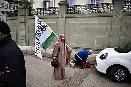 Una donna che indossa il niqab aspetta che il marito finisca la preghiera.