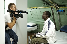 Un journaliste filme les conditions de vie dans les nouvelles tentes militaires servant d'hébergement d'urgence aux demandeurs d'asile. Cet homme n'arrive même pas à comprendre ce qui se passe. Il regarde timidement la caméra avec un sourire faux. Un journaliste filme les conditions de vie dans les nouvelles tentes militaires servant d'hébergement d'urgence aux demandeurs d'asile. Cet homme n'arrive même pas à comprendre ce qui se passe. Il regarde timidement la caméra avec un sourire faux.