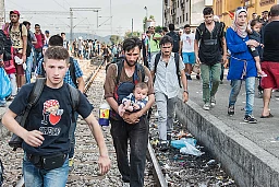 Gevgelija (Macedonia): un giovane siriano con in braccio il suo bambino si avvicina ai vagoni del convoglio appena giunto in stazione con la speranza di poterci salire insieme alla sua famiglia.