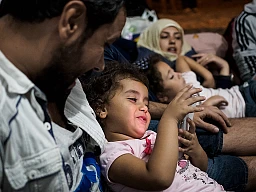 Una bambina gioca con il cellulare del padre in un campo di transito macedone.