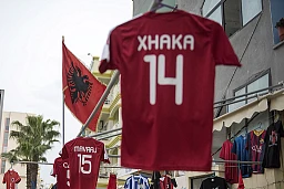 Des maillots et le drapeau albanais flottent au vent devant une boutique de rue. Des maillots et le drapeau albanais flottent au vent devant une boutique de rue.