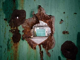 Stanytsia Luhanska, Ukraine / 21 novembre 2017. Vue à travers le trou percé par un éclat d'obus dans une clôture d'un village ukrainien proche de la ligne de front avec la République populaire séparatiste de Louhansk, dans la région de Louhansk. © Niels Ackermann / Lundi13 Stanytsia Luhanska, Ukraine / 21 novembre 2017. Vue à travers le trou percé par un éclat d'obus dans une clôture d'un village ukrainien proche de la ligne de front avec la République populaire séparatiste de Louhansk, dans la région de Louhansk. © Niels Ackermann / Lundi13