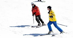 Verbier, 08.04.2017, High Five by Carlsberg, Jeune homme aveugle en veste jaune ave son moniteur derriere lui Verbier, 08.04.2017, High Five by Carlsberg, Jeune homme aveugle en veste jaune ave son moniteur derriere lui