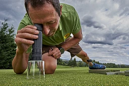 Der Chef-Greenkeeper auf dem Golfplatz Blumisberg schaut sich das Green mit einer Lupe an. Der Chef-Greenkeeper auf dem Golfplatz Blumisberg schaut sich das Green mit einer Lupe an.
