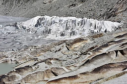 Entre rochers et glaces devenues grises, des couvertures pour garder le froid, recouvrent une grotte de glace.