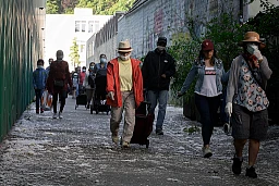 People in need rush to queue for a free food distribution on May 9, 2020 in Geneva as the COVID-19 pandemic casts a spotlight on the usually invisible poor people of Geneva, one of the world's most expensive cities.