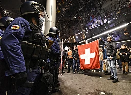 Des manifestants anti-mesures Covid déploient un drapeau suisse devant la police anti-émeute bernoise, à Berne, le 14 octobre 2021. Des manifestants anti-mesures Covid déploient un drapeau suisse devant la police anti-émeute bernoise, à Berne, le 14 octobre 2021.