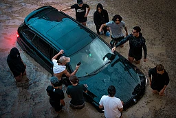 Des personnes tentent de sortir la voiture de l'eau. Sans succès