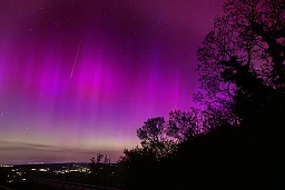 A meteor strikes in an aurora borealis above Lausanne and the Jura from the Tour de Gourze in Riex, Switzerland, May 11, 2024