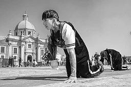Ein junger Mann pilgert auf Knien mit Blumen in einer Hand zur Basilika von Guadalupe. Ein junger Mann pilgert auf Knien mit Blumen in einer Hand zur Basilika von Guadalupe.